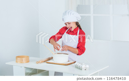 diligent approach. happy child cooking in kitchen. bake cookies in kitchen. professional and skilled baker. kid in chef uniform and hat. teen girl preparing dough. making cake by recipe. time to eat 116478410
