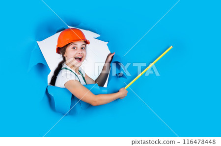 happy kid engineer with tape measure tool in hard hat, workshop 116478448