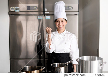 A young female chef doing a fist pump in the kitchen 116478682