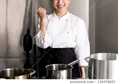A young female chef doing a fist pump in the kitchen 116478683