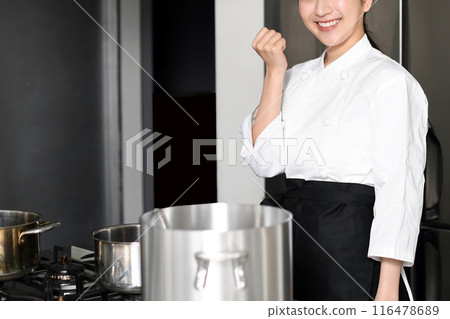 一位年輕的女廚師在廚房裡做拳頭泵 一位年輕的女廚師在廚房裡做拳頭泵 116478689