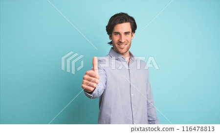 Happy man showing thumbs up in blue studio 116478813