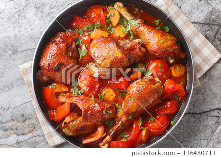 Slow cooked rooster with bell peppers, onions and carrots in tomato sauce close-up in a pan. Horizontal top view Slow cooked rooster with bell peppers, onions and carrots in tomato sauce close-up in a pan. Horizontal top view 116480711