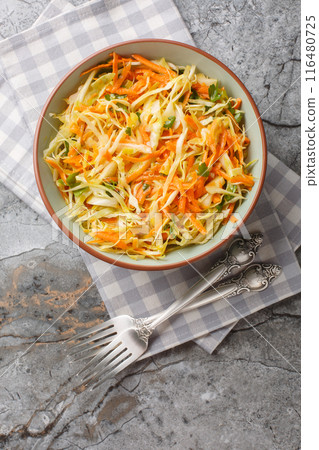 Fresh salad of white cabbage with carrots dressed with olive oil close-up in a bowl. Vertical top view Fresh salad of white cabbage with carrots dressed with olive oil close-up in a bowl. Vertical top view 116480725