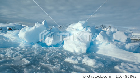Close up snow-covered ice on frozen ocean surface in Antarctica. Mountains in background. Cold winter wild nature landscape. Discover beauty of South Pole. Antarctic travel and exploration panorama Close up snow-covered ice on frozen ocean surface in Antarctica. Mountains in background. Cold winter wild nature landscape. Discover beauty of South Pole. Antarctic travel and exploration panorama 116480862