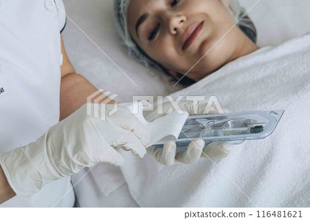 cosmetologist prepares tools from a sterile package, ensuring all equipment is ready and safe for a facial treatment cosmetologist prepares tools from a sterile package, ensuring all equipment is ready and safe for a facial treatment 116481621