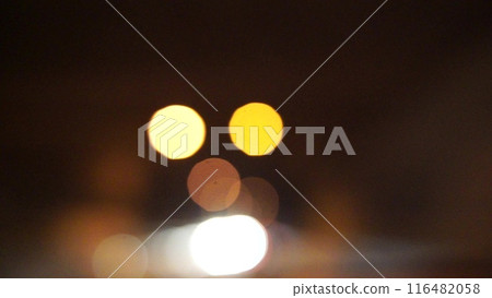 Blurred car lights bokeh in the evening city. Defocused headlights and street lighting at night. Moving bokeh circles of cars at night. Blurred city traffic background Blurred car lights bokeh in the evening city. Defocused headlights and street lighting at night. Moving bokeh circles of cars at night. Blurred city traffic background 116482058