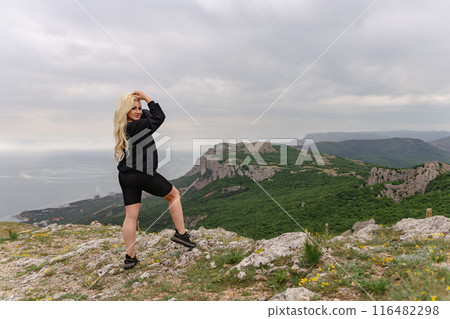 A woman is posing on a mountain top with a black sweatshirt on 116482298