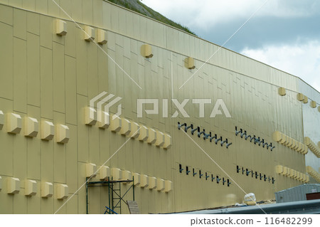 A large building with many windows and vents. The building is yellow and has a lot of windows. A large building with many windows and vents. The building is yellow and has a lot of windows. 116482299
