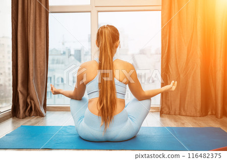 Young woman meditating at home. Girl practicing yoga in class. Relaxation at home, body care, balance, healthy lifestyle, meditation, mindfulness, recreation, workout, fitness, training concept 116482375