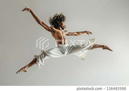 Male dancer in white pants performs mid air leap 116483500