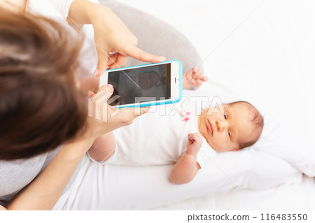 Mom Taking Photo of Newborn Baby with Smartphone.. Mom Taking Photo of Newborn Baby with Smartphone.. 116483550