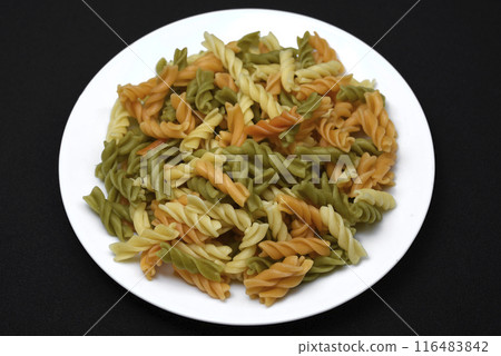 Multicolored pasta on a white plate. Boiled pasta. Multicolored pasta on a white plate. Boiled pasta. 116483842