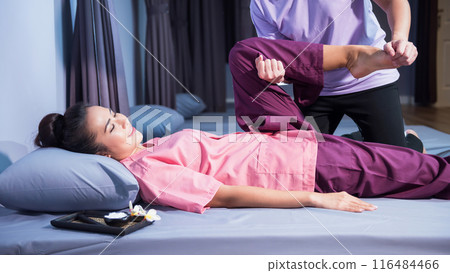 Thai massage by stretching foot and leg to woman at spa bed Thai massage by stretching foot and leg to woman at spa bed 116484466