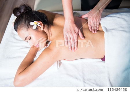 Thai oil back massage to young Asian topless woman on bed in spa 116484468