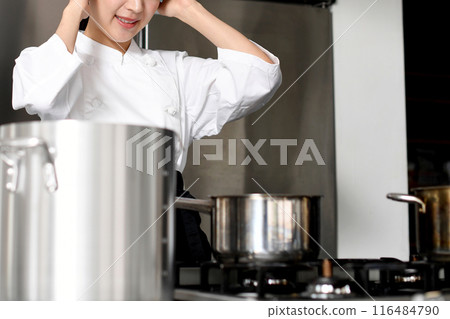 一位年輕的亞洲女廚師在廚房裡遇到了麻煩。 一位年輕的亞洲女廚師在廚房裡遇到了麻煩。 116484790