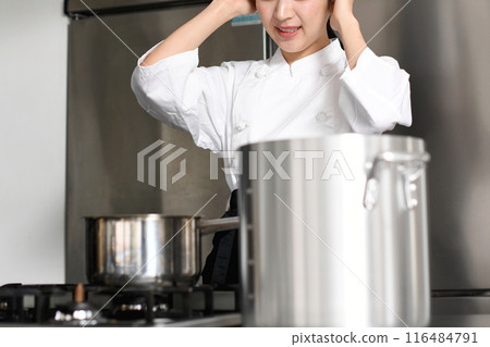 一位年輕的亞洲女廚師在廚房裡遇到了麻煩。 一位年輕的亞洲女廚師在廚房裡遇到了麻煩。 116484791