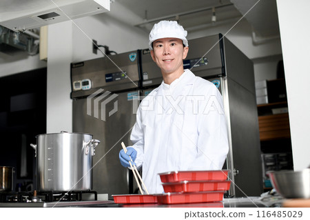 男性烹飪人員將食物裝入便當盒 男性烹飪人員將食物裝入便當盒 116485029