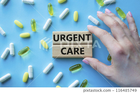 Urgent Care symbol. Concept word Urgent Care on wooden blocks. Beautiful blue background with pills. Doctor Hand. Medicine and Urgent Care concept. Copy space 116485749