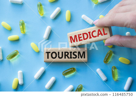 Medical Tourism symbol. Concept word Medical Tourism on wooden blocks. Beautiful blue background with pills. Doctor Hand. Medicine and Medical Tourism concept. Copy space 116485750