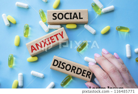 Social Anxiety Disorder symbol. Concept words Social Anxiety Disorder on wooden blocks. Beautiful blue background with pills. Doctor hand. Healthcare and Social Anxiety Disorder concept. Copy space. 116485771