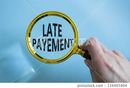 Late payment symbol. Concept word Late payment on magnifying glass. Businessman hand. Beautiful blue background. Business and Late payment concept. Copy space 116485804