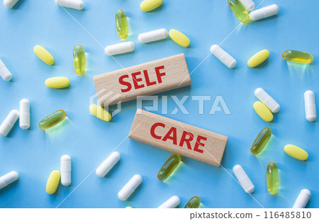 Self Care symbol. Concept word Self Care on wooden blocks. Beautiful blue background with pills. Business and Self Care concept. Copy space 116485810