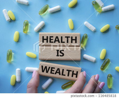 Health is Wealth symbol. Concept word Health is Wealth on wooden blocks. Doctor hand. Beautiful blue background with pills. Medicine and Health is Wealth concept. Copy space 116485818