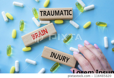 Traumatic Brain Injury symbol. Concept words Traumatic Brain Injury on wooden blocks. Beautiful blue background with pills. Doctor hand. Healthcare and Traumatic Brain Injury concept. Copy space. 116485820