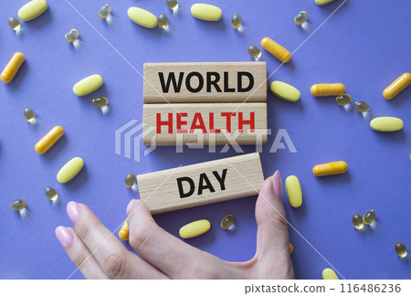World Health Day symbol. Concept words World Health Day on wooden blocks. Beautiful purple background with pills. Doctor hand. Healthcare and World Health Day concept. Copy space. 116486236