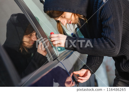 Thieft man holding screwdriver breaking into car Thieft man holding screwdriver breaking into car 116486265