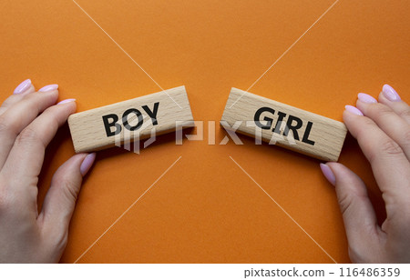 Boy or Girl symbol. Concept word Boy or Girl on wooden blocks. Man hand. Beautiful orange background. Gender and Boy or Girl concept. Copy space 116486359