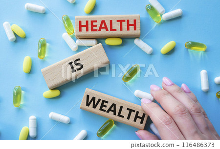 Health is Wealth symbol. Concept word Health is Wealth on wooden blocks. Doctor hand. Beautiful blue background with pills. Medicine and Health is Wealth concept. Copy space 116486373