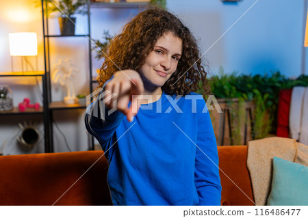 Happy woman sitting on sofa and pointing with both hands makes selecting and choosing gesture Happy woman sitting on sofa and pointing with both hands makes selecting and choosing gesture 116486477