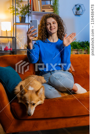Woman taking selfie on smartphone waving hello communicating video call online recording stories Woman taking selfie on smartphone waving hello communicating video call online recording stories 116486478