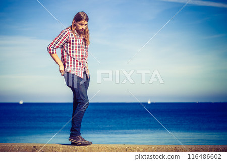 Man walking relaxed on stone wall by seaside Man walking relaxed on stone wall by seaside 116486602