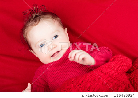 Little baby on red blanket in bed 116486924