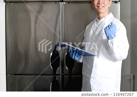 A man wearing sanitary clothing poses in the kitchen A man wearing sanitary clothing poses in the kitchen 116487267