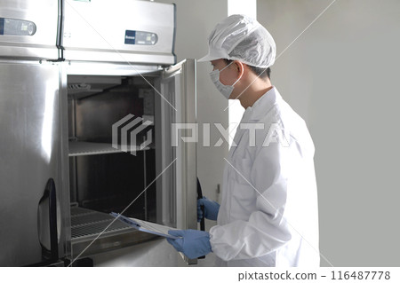 A man in hygiene clothing opening a commercial refrigerator 116487778