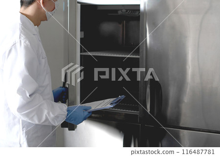 A man in hygiene clothing opening a commercial refrigerator A man in hygiene clothing opening a commercial refrigerator 116487781