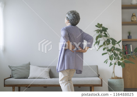 A woman in her 80s holding her hips with both hands, back view 116488025