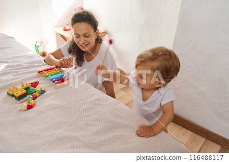 Mother and child playing with educational toys in a bright room Mother and child playing with educational toys in a bright room 116488117