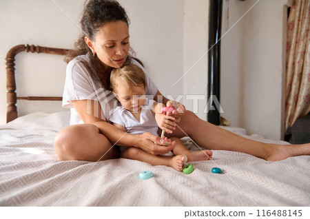 Mother and baby playing together on bed, bonding and enjoying quality time 116488145