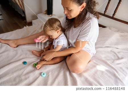Mother and toddler playing together on the bed in a cozy home environment 116488148