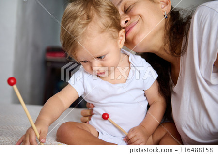 Mother and baby bonding together and playing with toys in a cozy home setting Mother and baby bonding together and playing with toys in a cozy home setting 116488158