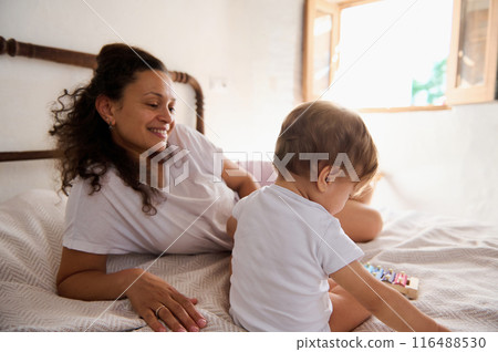 Mother and child enjoying quality time together in a cozy bedroom setting Mother and child enjoying quality time together in a cozy bedroom setting 116488530