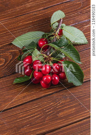 ripe cherry on a branch on a wooden table 116490183