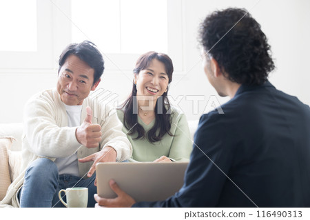 A smiling couple in their 50s listening to a salesman's explanation about investments, insurance, real estate, etc. A smiling couple in their 50s listening to a salesman's explanation about investments, insurance, real estate, etc. 116490313