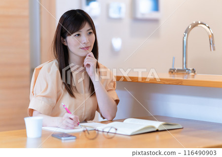 Middle-aged woman studying at the dining table 116490903