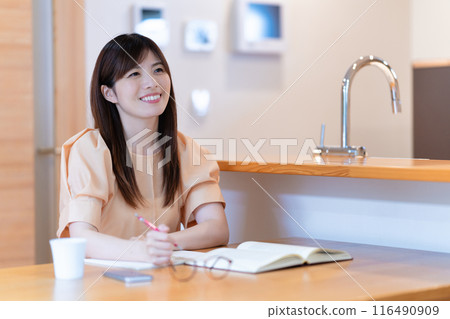 Middle-aged woman studying at the dining table 116490909